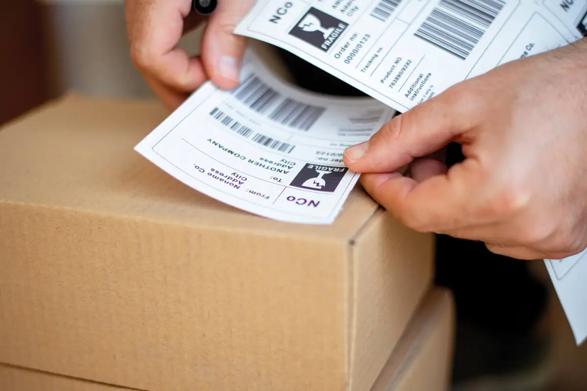 White shipping label being applied on a cardboard box